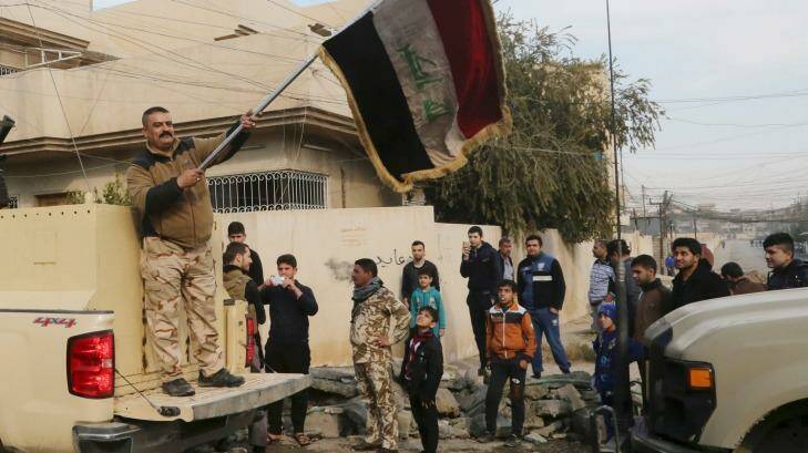 An Iraqi soldier waves the national flag as security forces patrol on the eastern side of Mosul, Iraq. Photo: PA