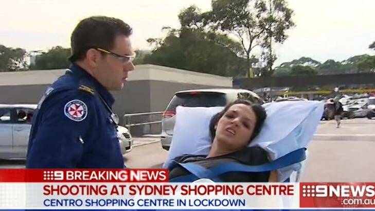 A woman is wheeled away by paramedics after the shooting at Bankstown Central Shopping Centre. Photo: Channel Nine
