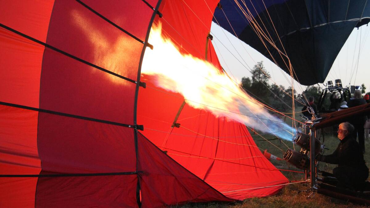 There she rises … one of Balloon Aloft’s pilots, Ewan Roberts, applies the heat.