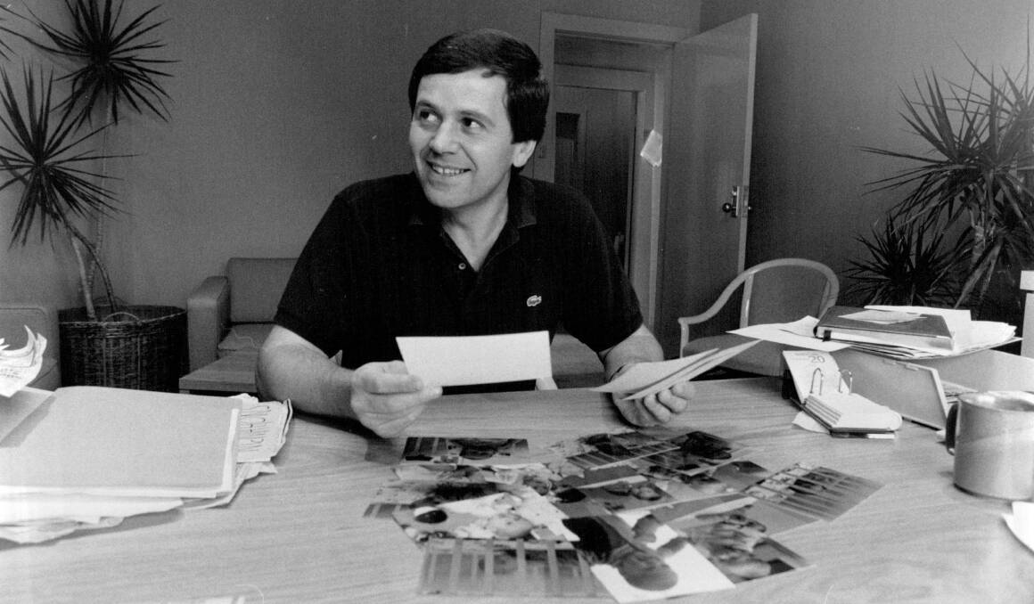 HAPPY SNAPS: Ray Martin at his desk at Channel 9 in 1985 looking at photos of his baby. Photo: Ross Anthony/Fairfax Media
