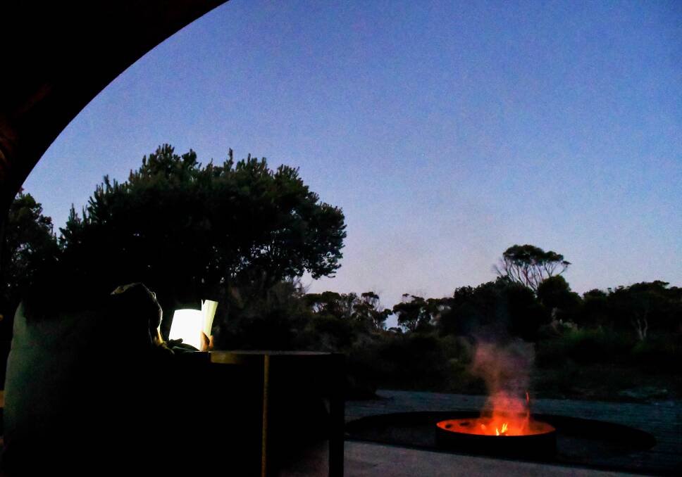 A tour member reads in front of the fire at krakani lumi. 