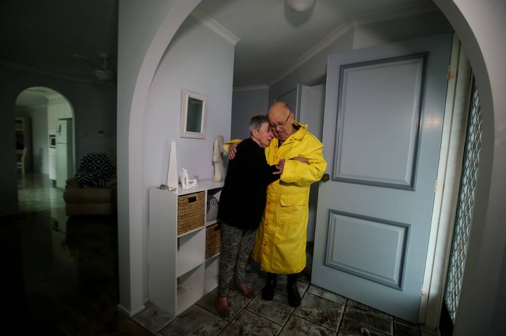 Sad: Gerringong couple Hazel and Bernie Gardiner console each other during a break from dealing with the water that rushed into their home on Saturday. Picture: Sylvia Liber