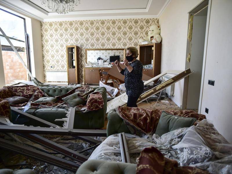 An Azerbaijani surveys her damaged house in the city of Ganja after Armenian rocket fire.